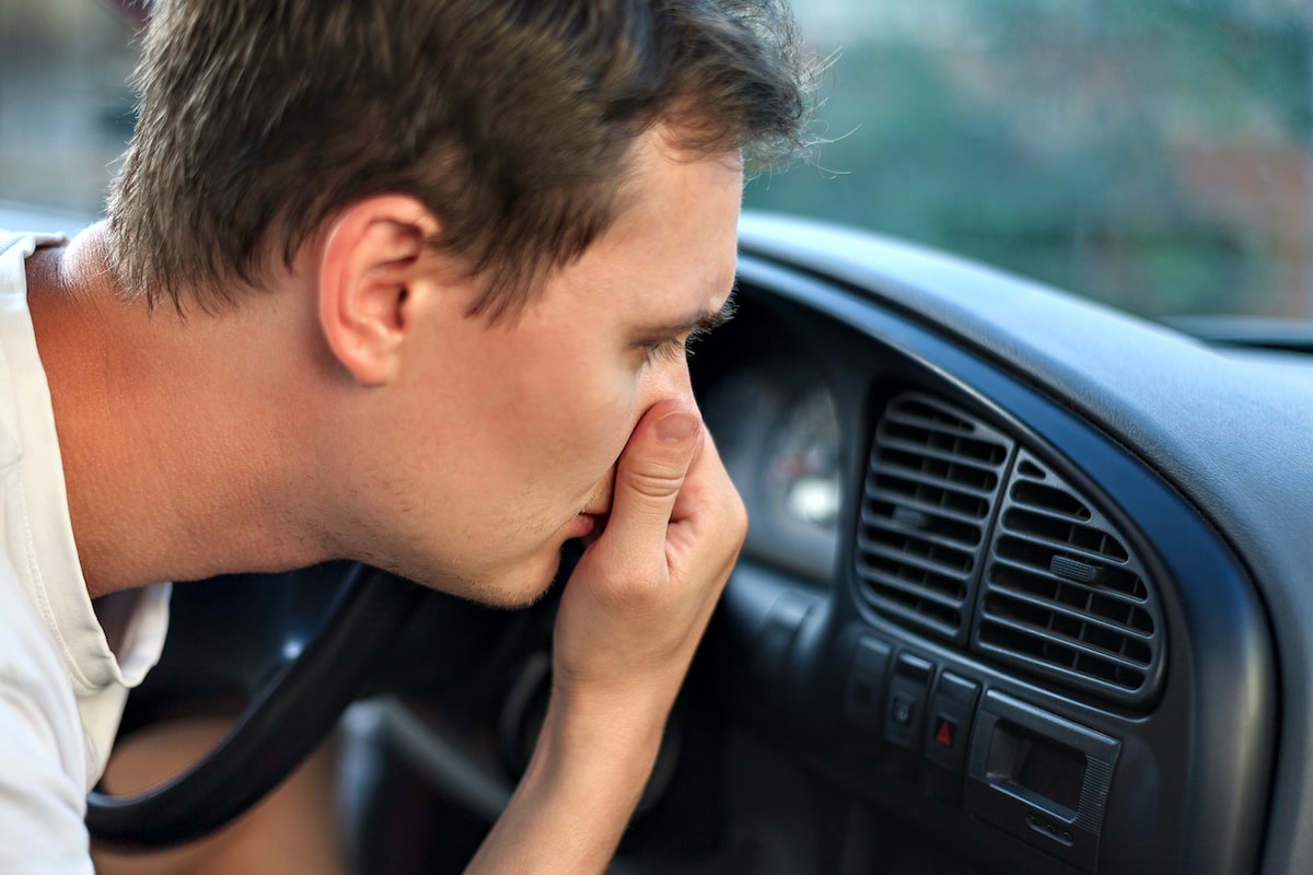 car making funny smell with man holding nose over ac