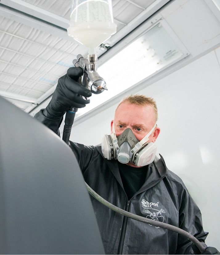 Mackins-auto-painting-14 mackins paint technician wearing a mask and painting a vehicle