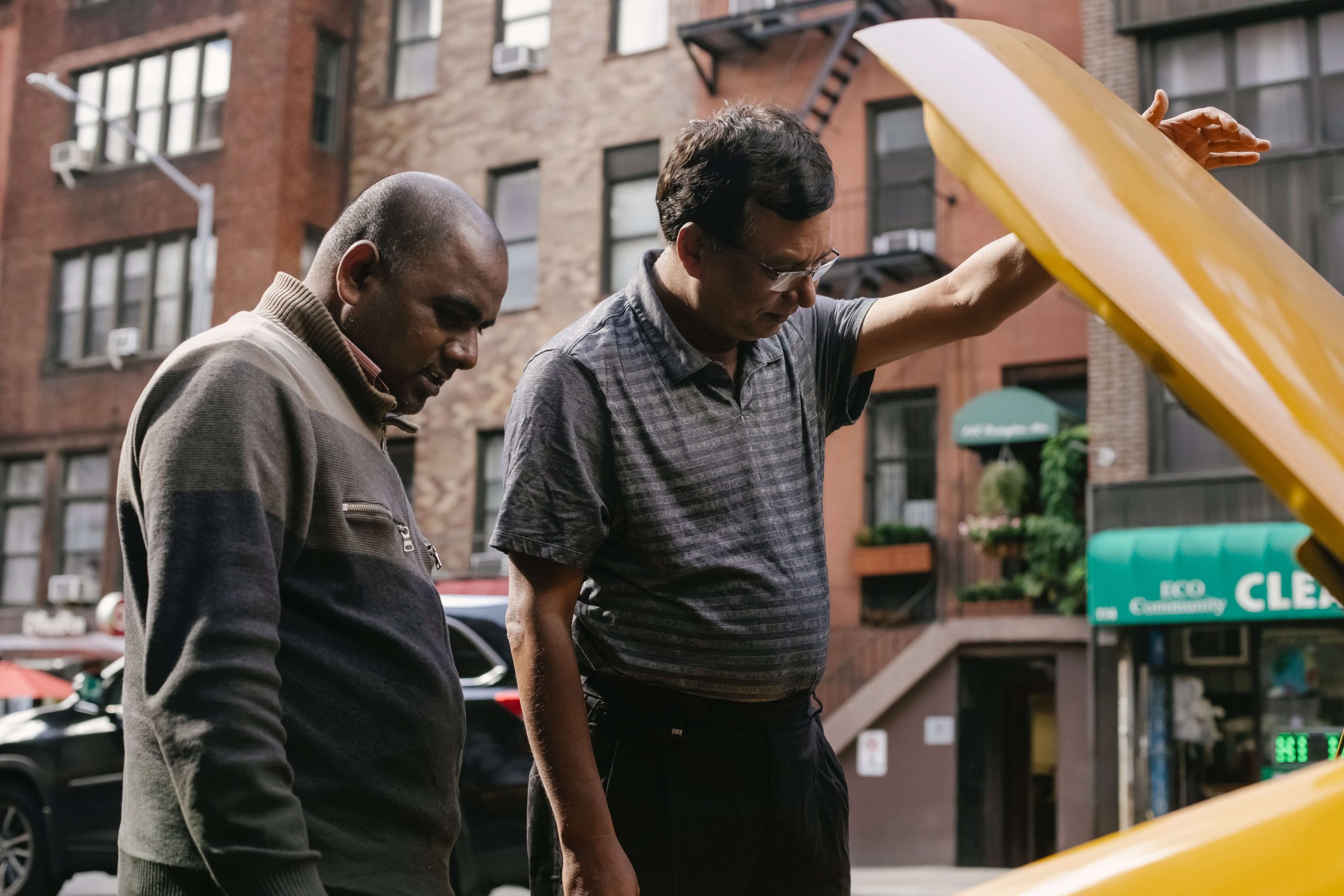 Two men looking under hood of a car
