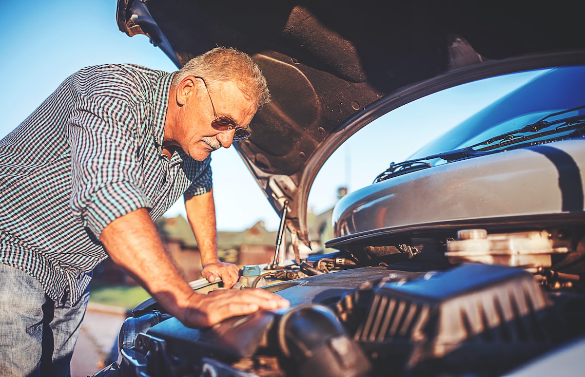 old man checking car engine for signs of damage
