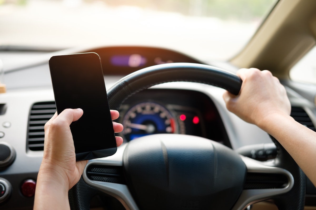 person driving car while holding cell phone
