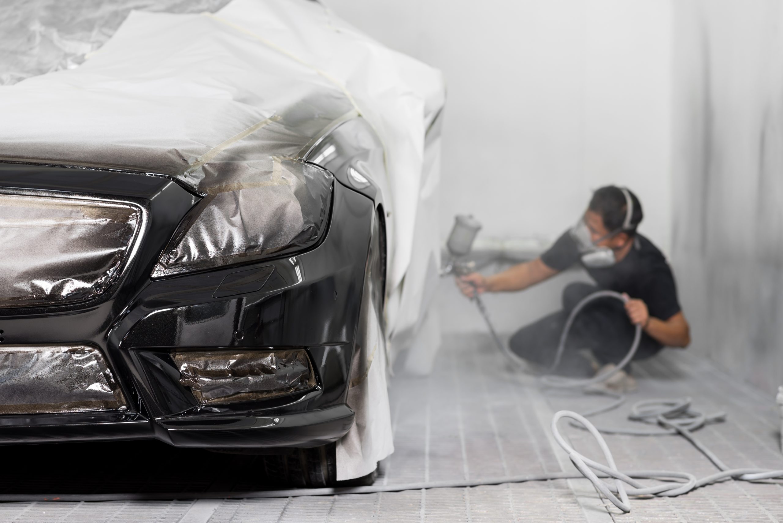 technician spraying paint on a black vehicle