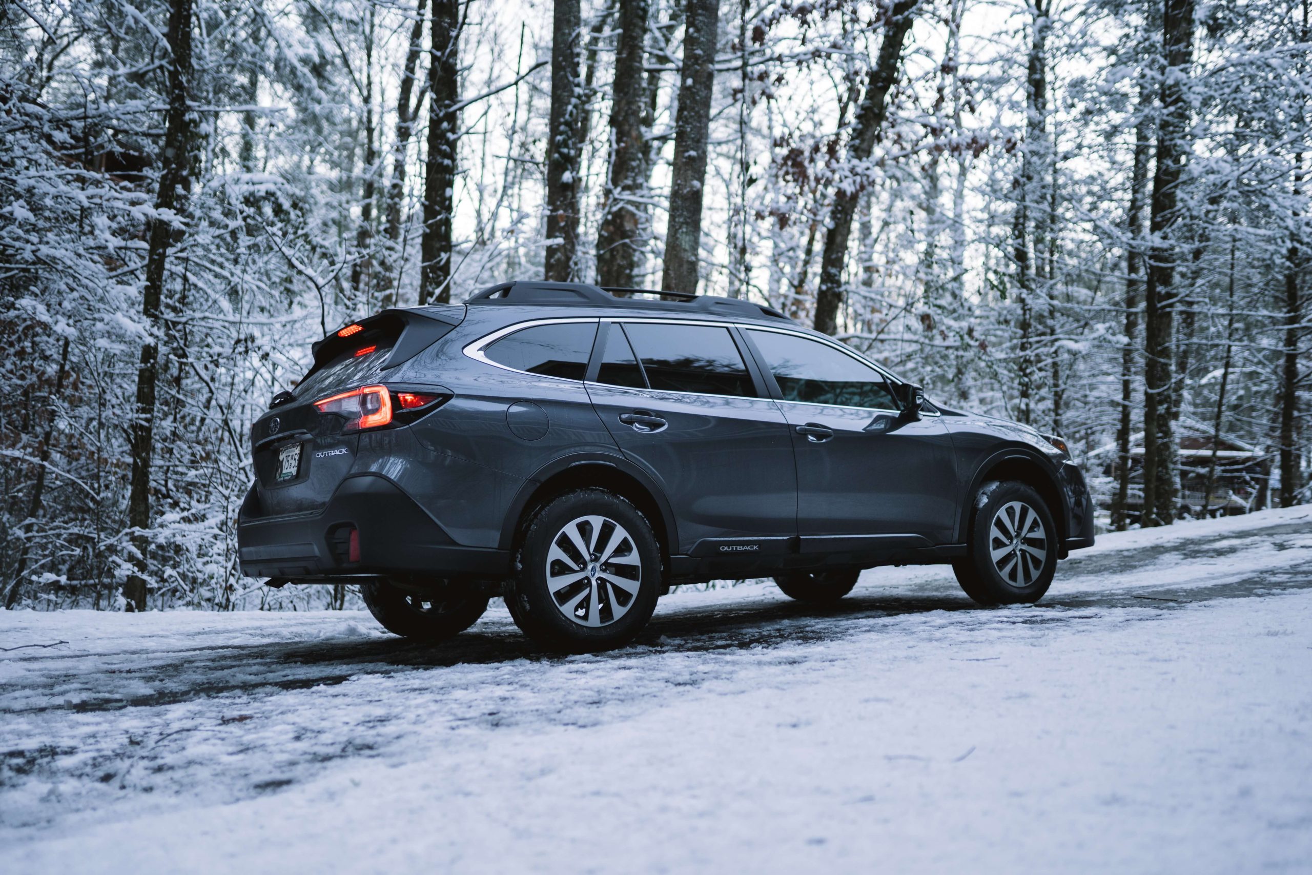 Subaru driving on snowy road in woods